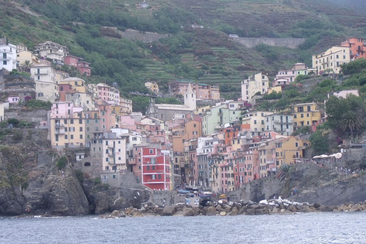 Riomaggiore met felgekleurde huizen en schilderachtige kliffen die in de diepblauwe zee storten