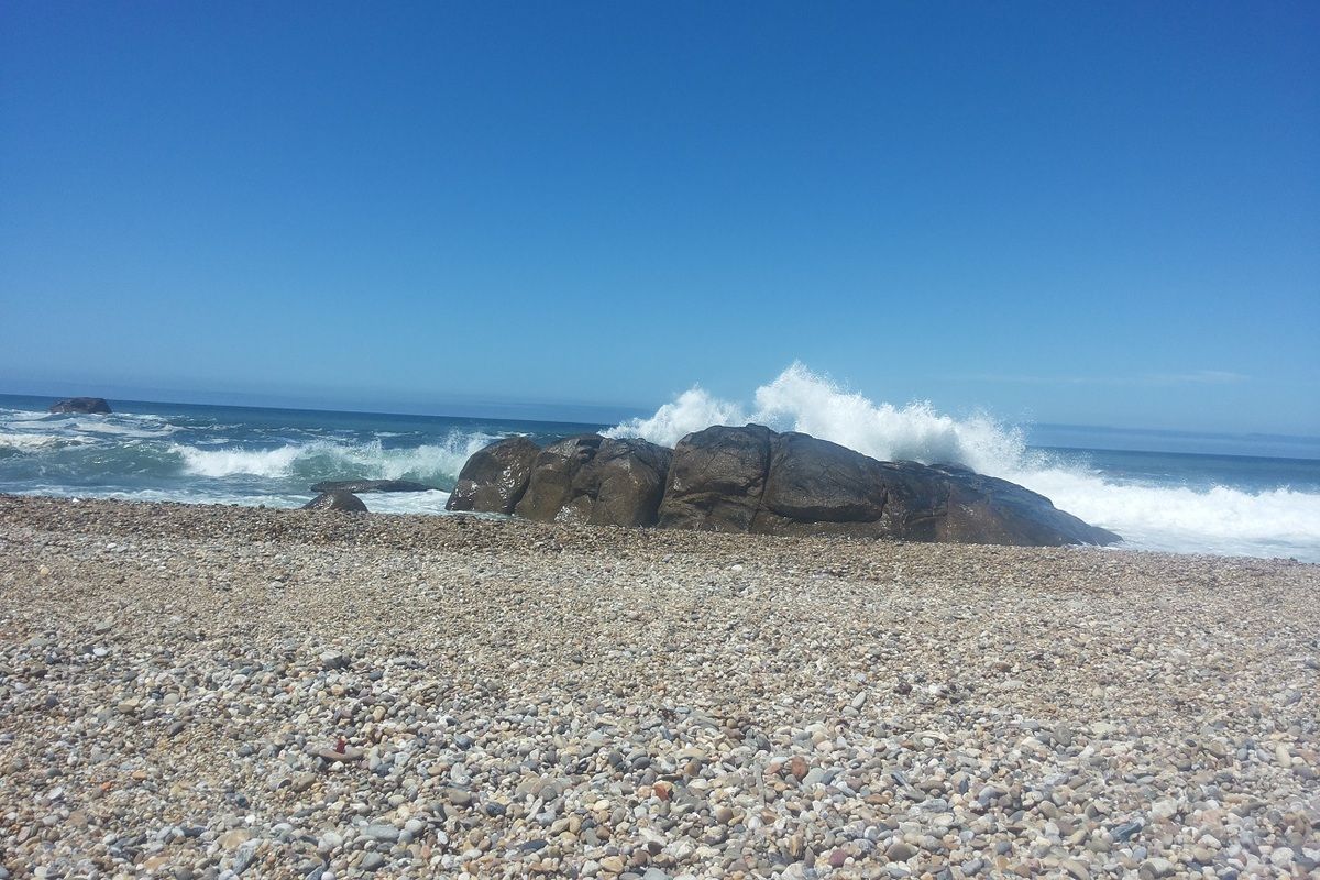 Het kiezelstrand met uitspattend water van de zee