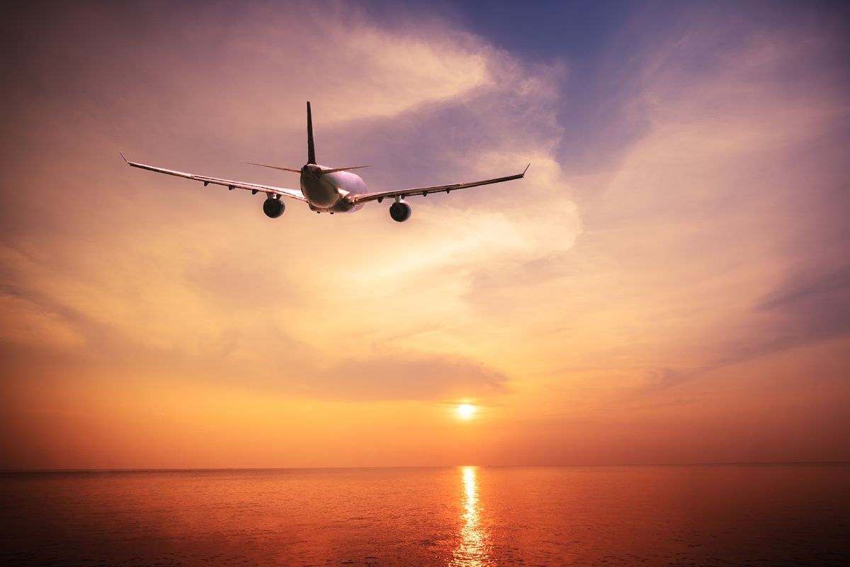 Vliegtuig boven de oceaan bij zonsondergang