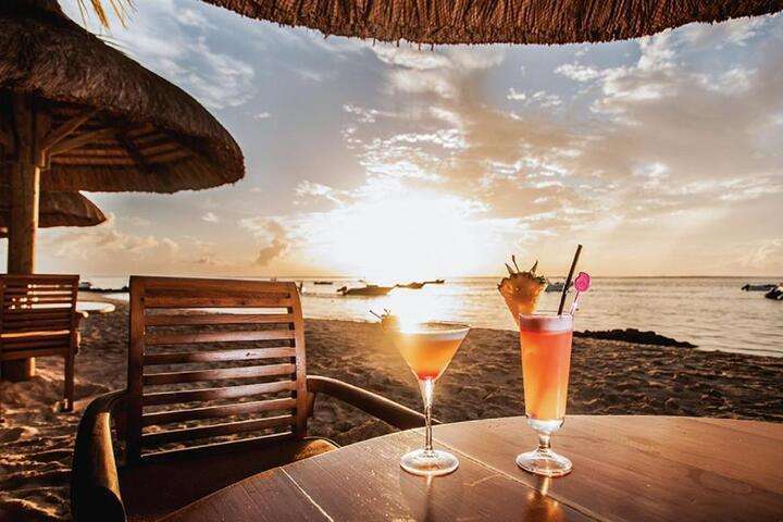 Geniet van een drankje op het strand bij zonsondergang